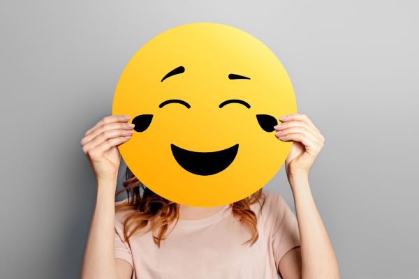 Emoji demonstrando risada tapando o rosto de uma moça